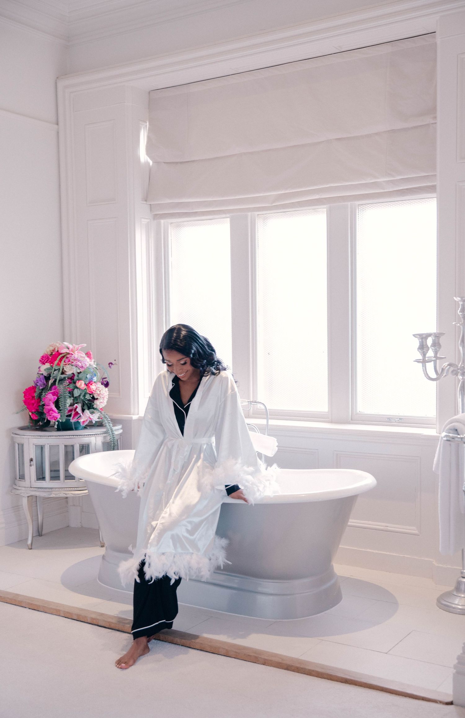Bright white bathroom interior with modern bathtub and large windows.