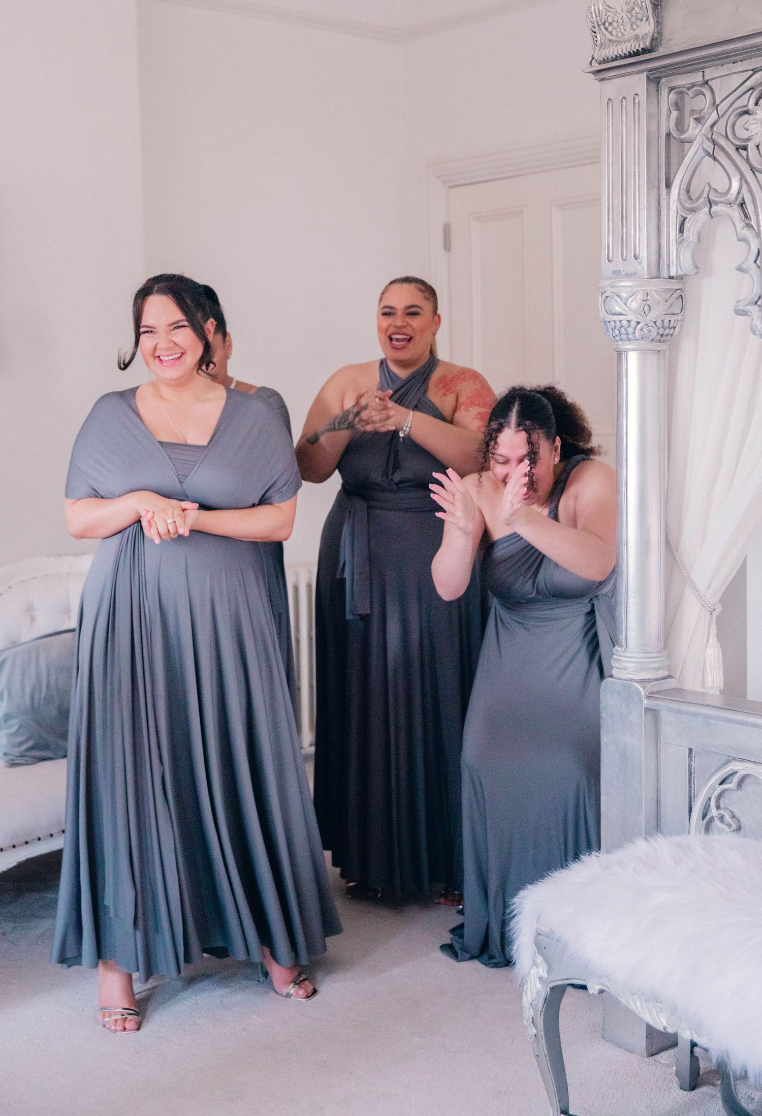 Bridesmaids in gray dresses sharing joyful moments during wedding preparations.
