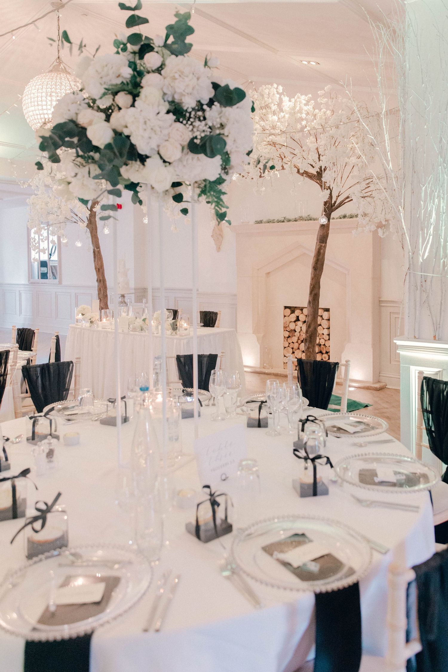 Elegant white wedding reception venue with hanging greenery and crystal chandeliers creating a romantic atmosphere.