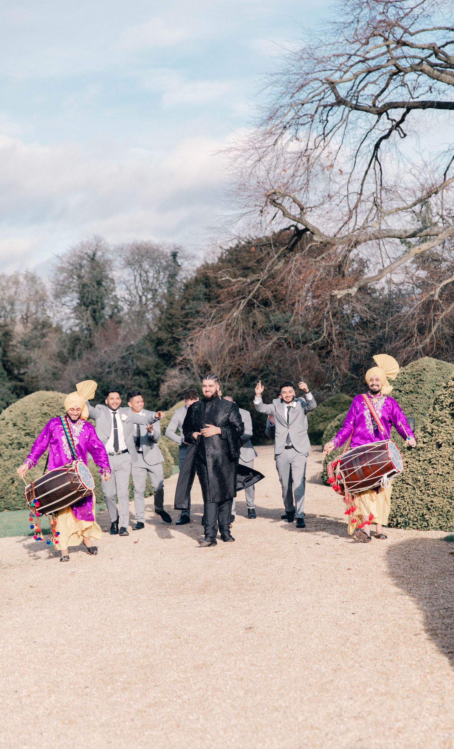 Wedding party gathered outdoors with colorful attire against winter landscape.