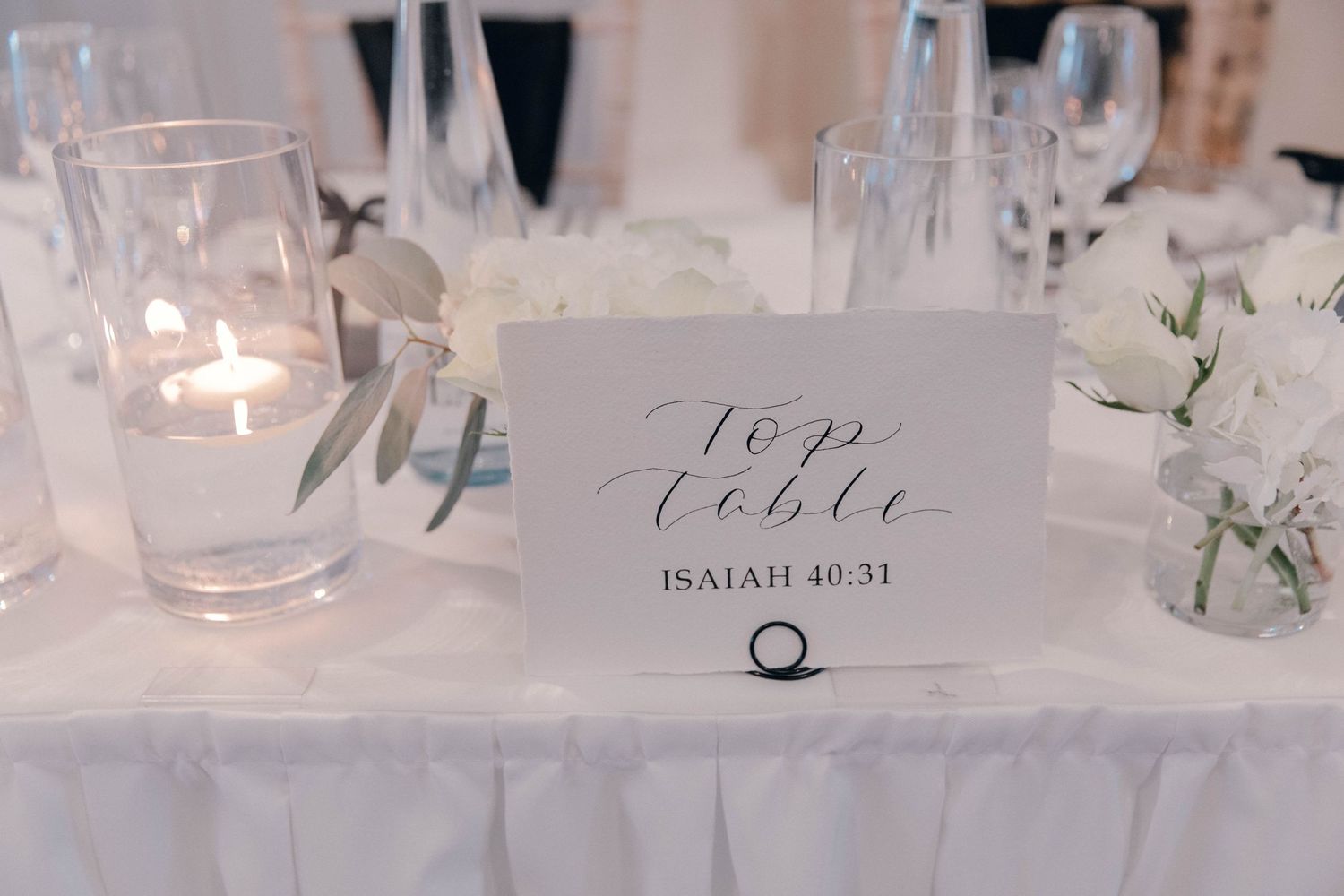 Wedding reception table settings with handwritten place cards and elegant glassware.