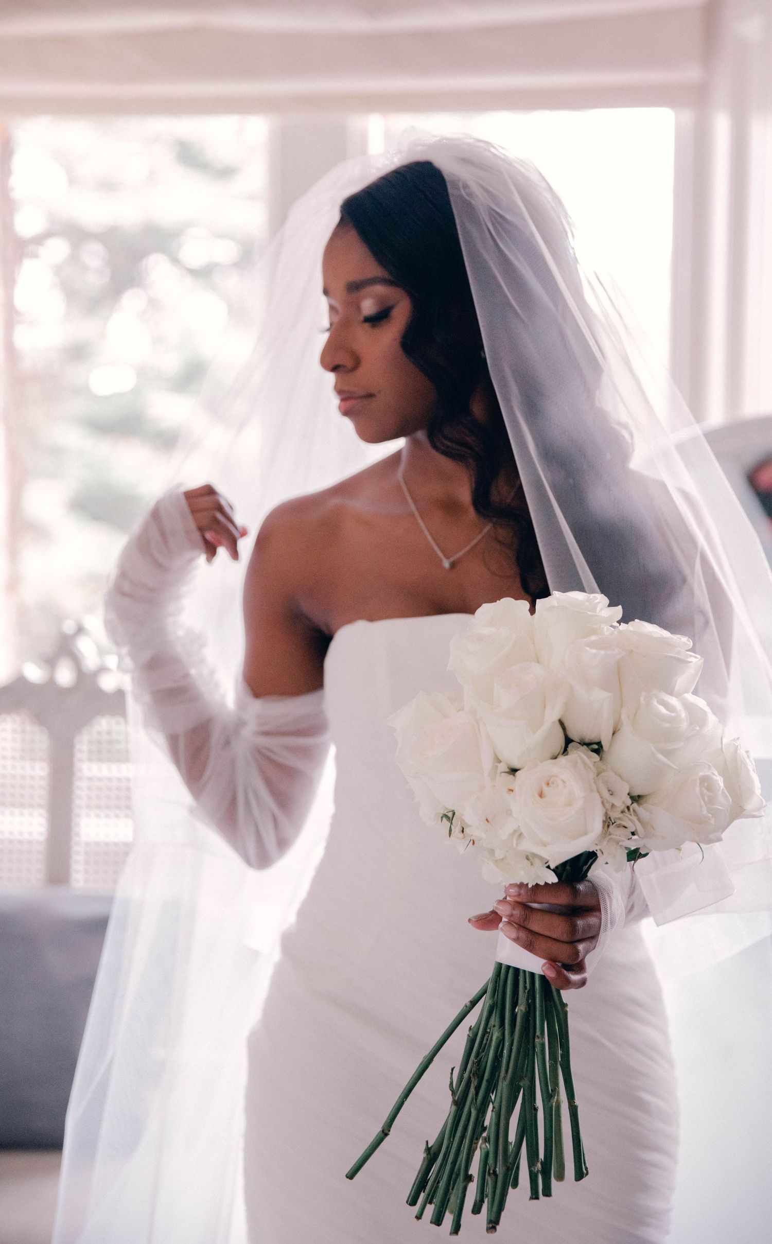 Artistic bridal portraits with white roses and flowing veil in natural light.