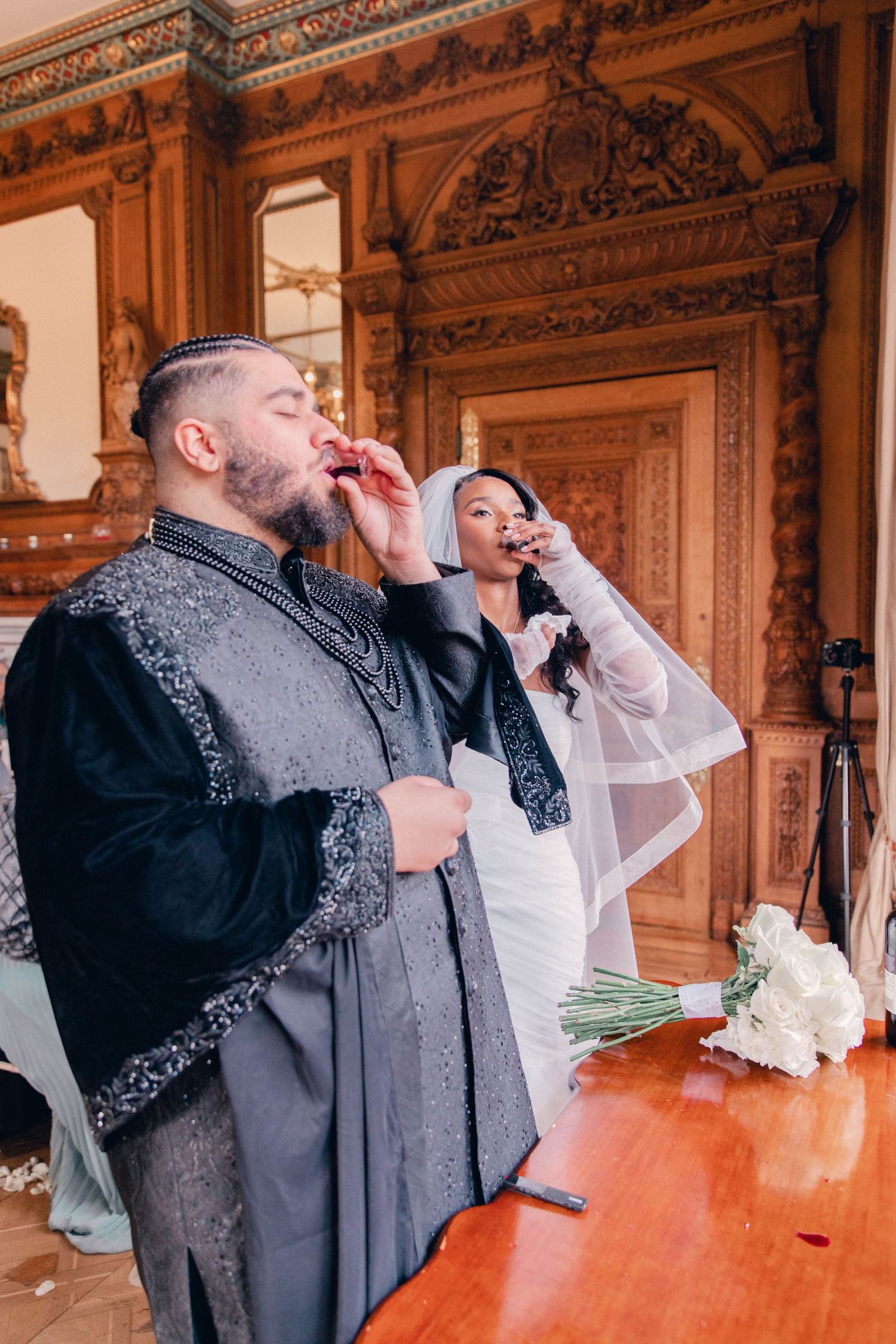 Wedding celebration in a luxurious vintage ballroom with carved wooden details and grand decor.