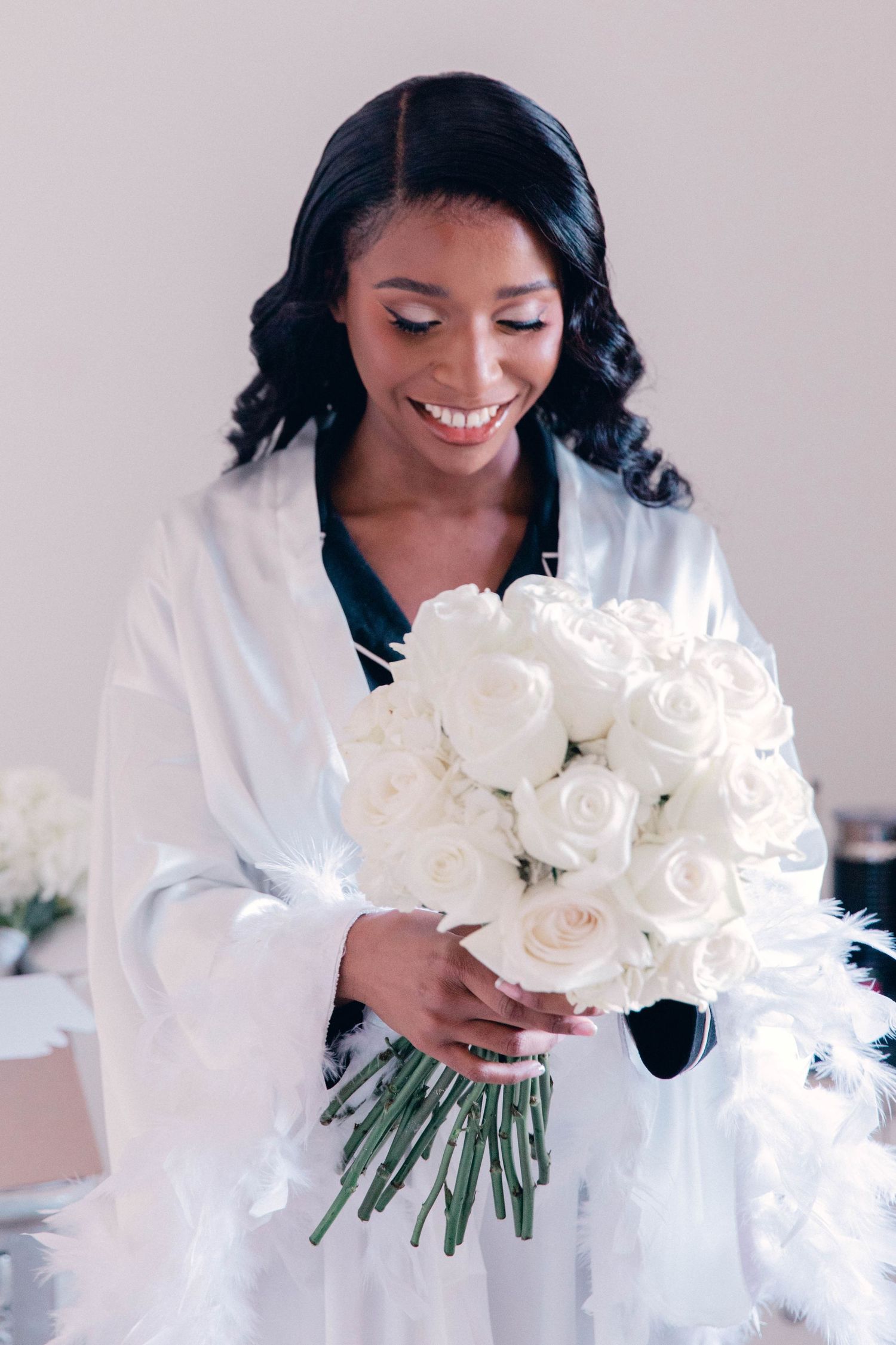Person in white robe holding beautiful bouquet of white roses.