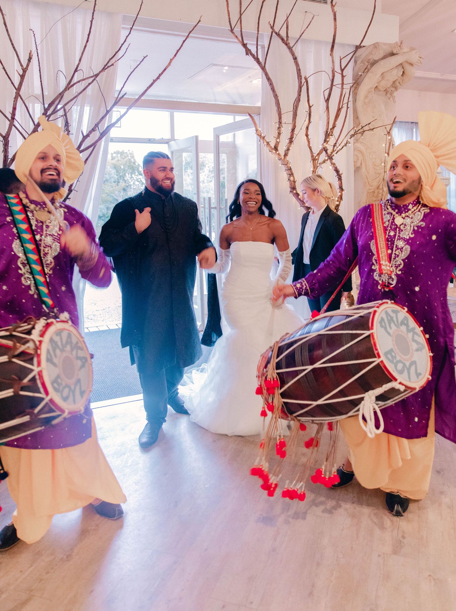 Wedding guests gathered under decorative white branches with red heart ornaments.