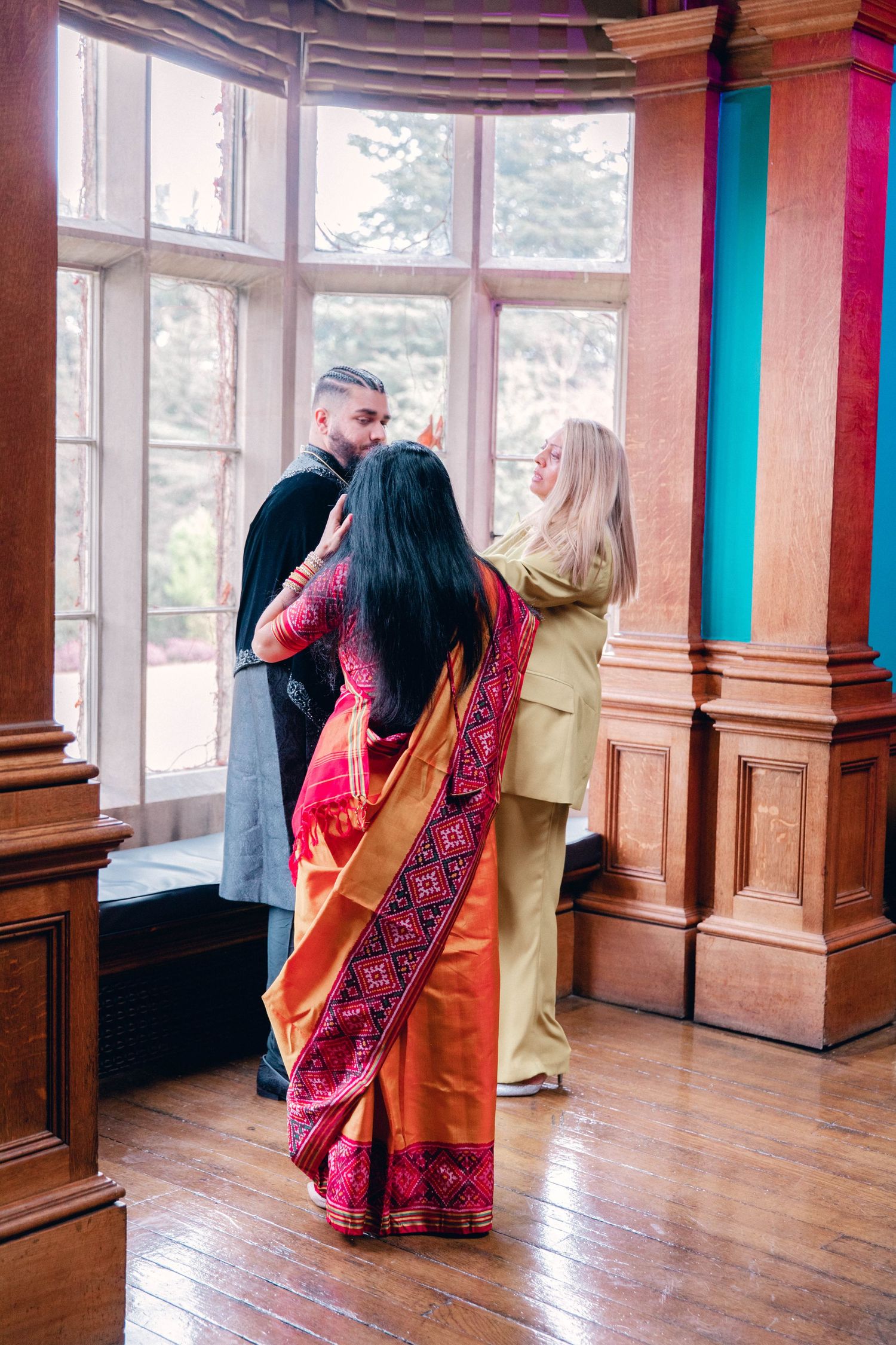 Couple dancing together in an elegant room with wooden panels and large windows.