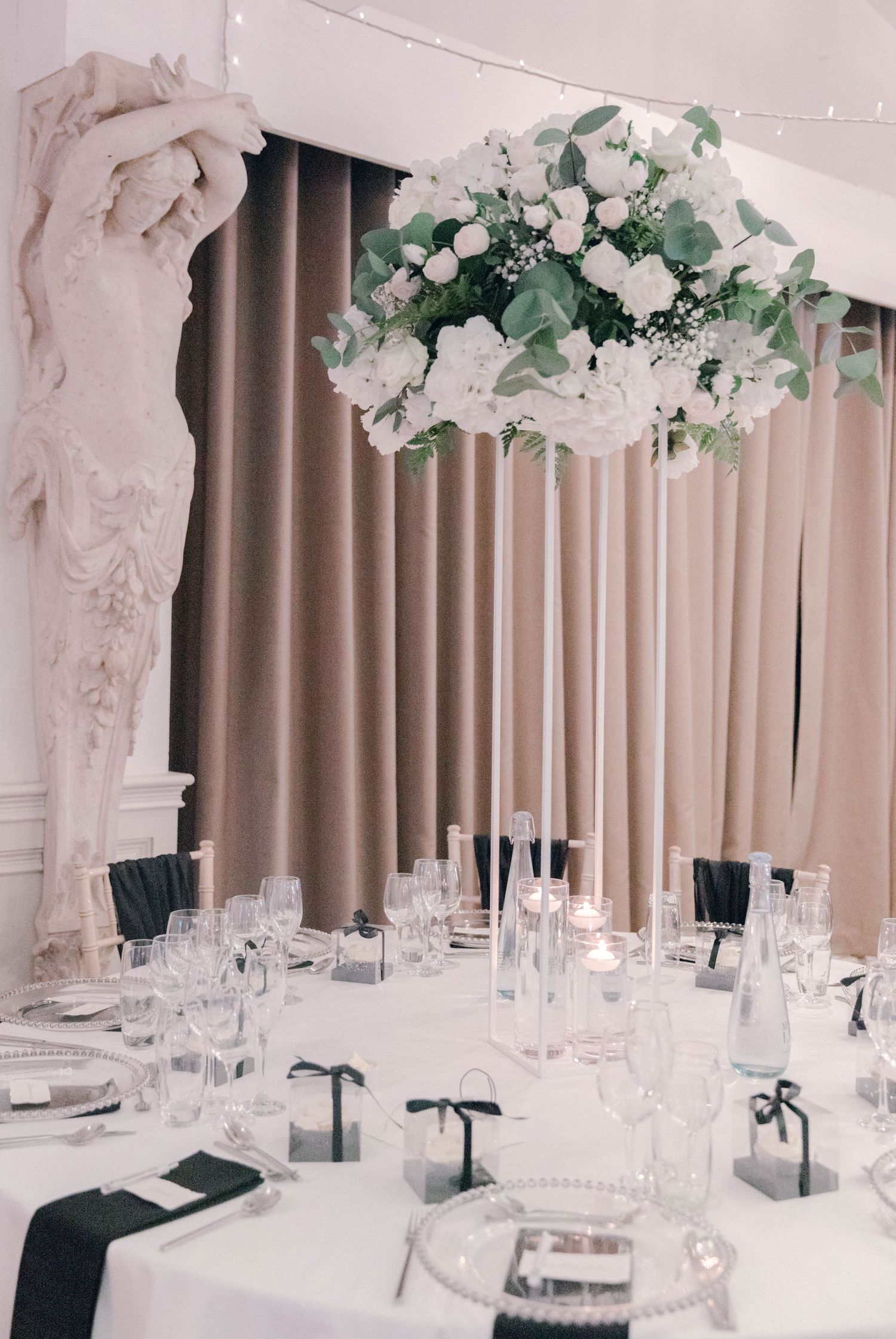 Elegant white wedding reception tables with floral arrangements and crystal place settings.