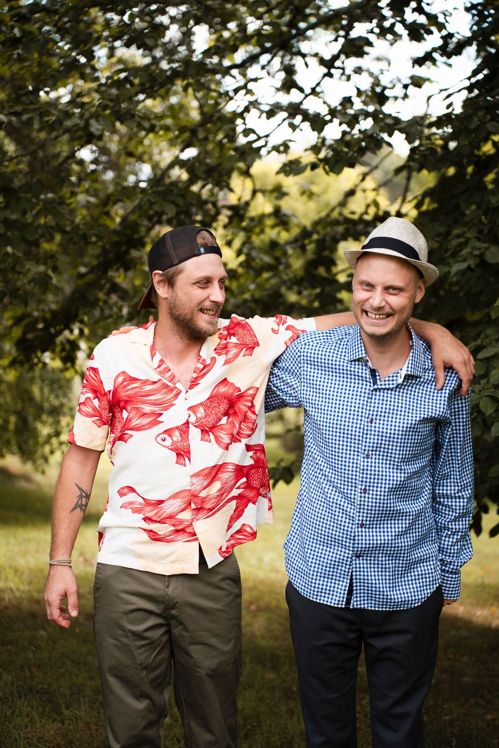 Two friends in casual summer attire sharing a laugh while walking through a park.