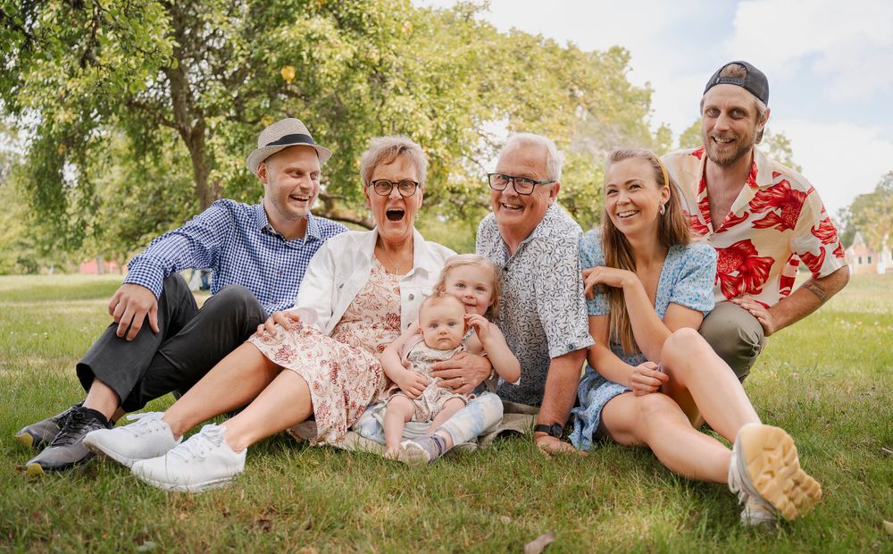 Family gathering on grass enjoying a sunny summer day in casual attire.