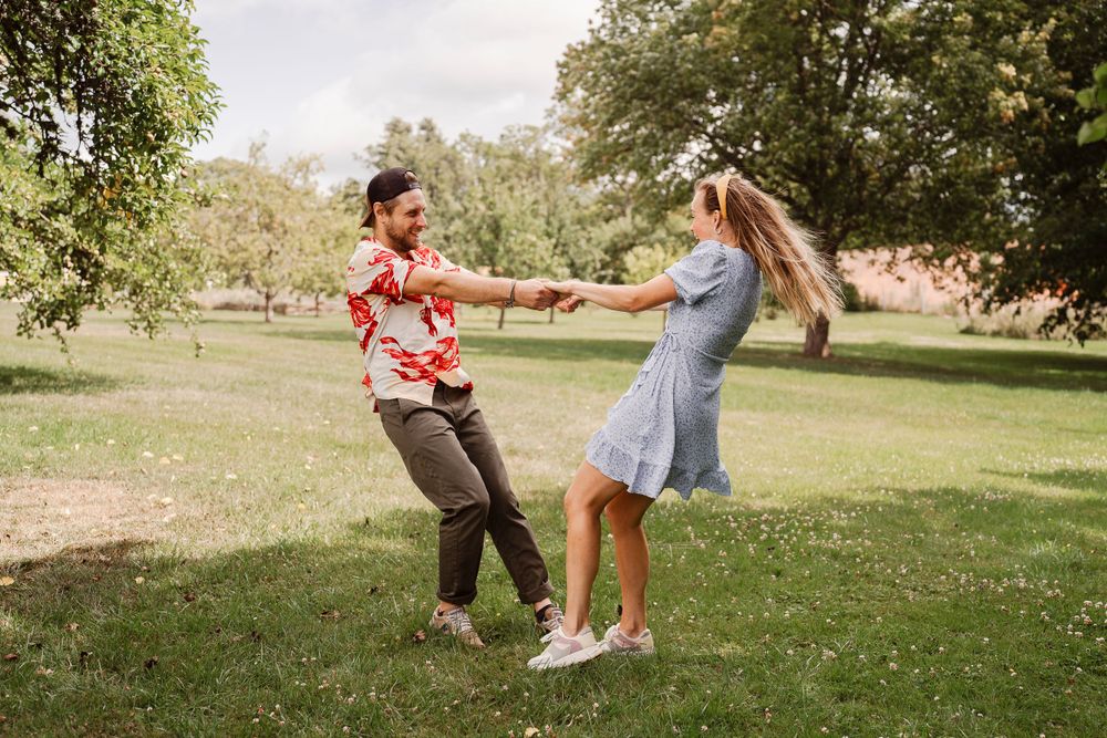 Playful dancing scene in a park with people in summer clothing.
