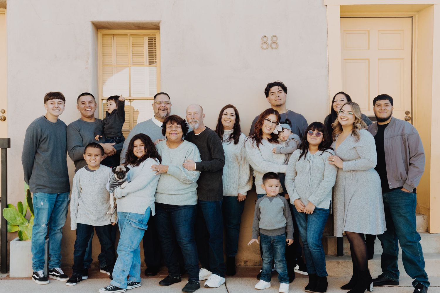 Extended family wearing coordinated blue and white outfits posed together for a professional portrait session.