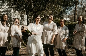 Bridal party in coordinated neutral dresses posing together in garden setting.