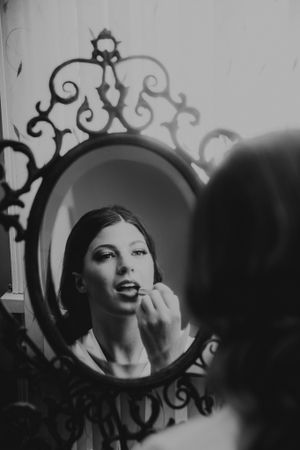 Wedding preparation moment captured in ornate vintage mirror reflection.