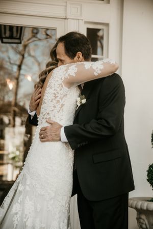 An emotional embrace captured during a wedding ceremony against a white backdrop.