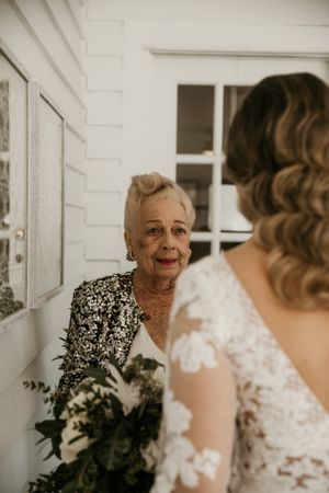 Emotional wedding moment captured on white porch with vintage styling.