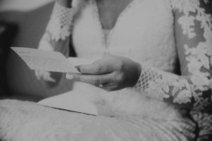 Close up of bride in lace dress reading a handwritten note.