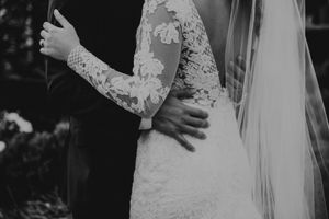 Black and white capture of wedding couple's intimate embrace showing detailed lace dress.
