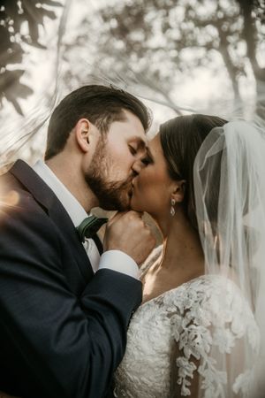 Dreamy outdoor wedding portrait capturing a tender moment between newlyweds with natural lighting.