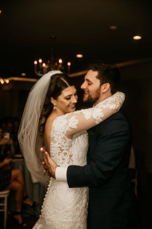 A romantic wedding dance captured in warm lighting shows the couple embracing on their special day.