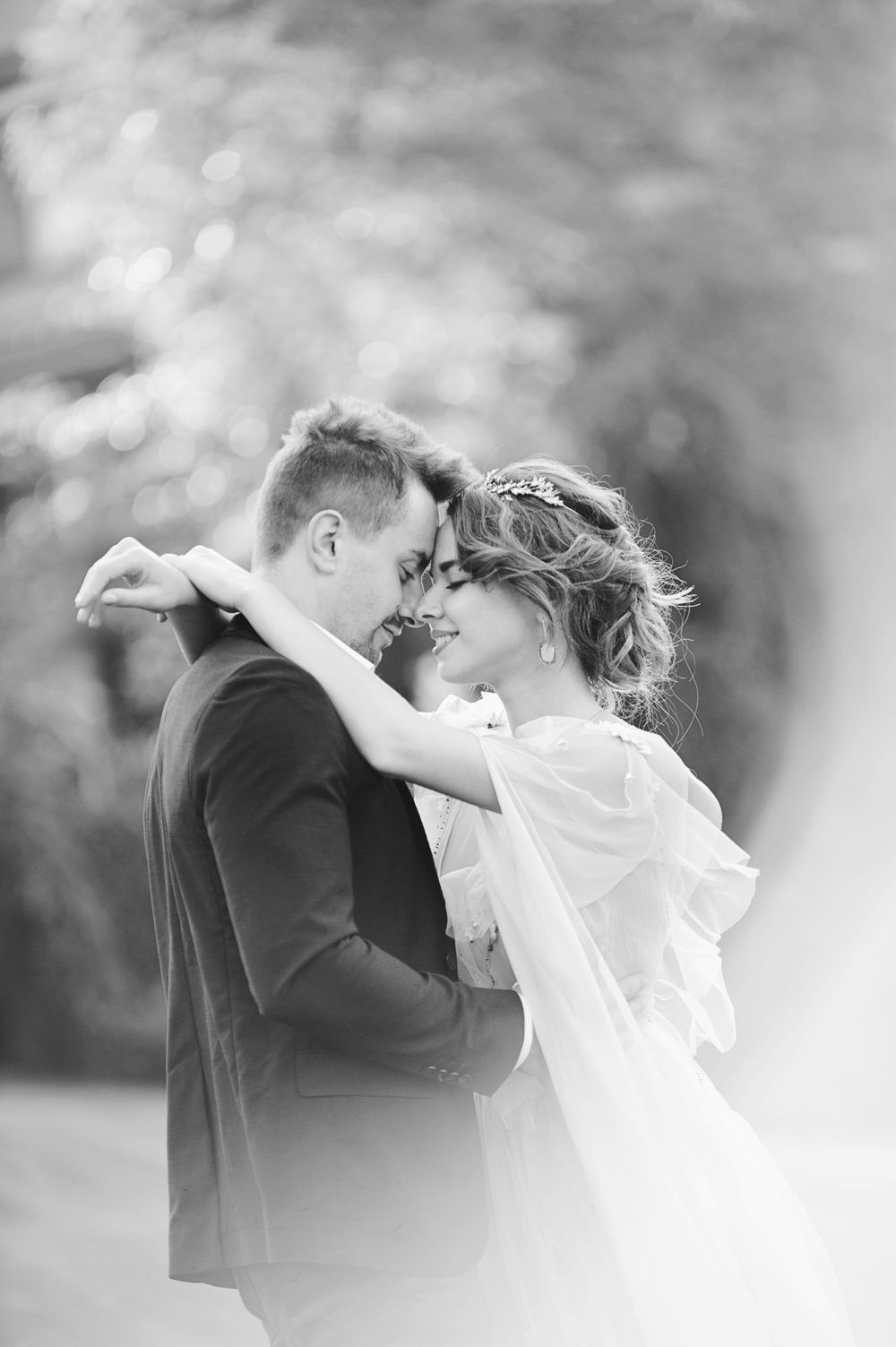 Black and white wedding portrait of a bride and groom sharing an intimate moment outdoors