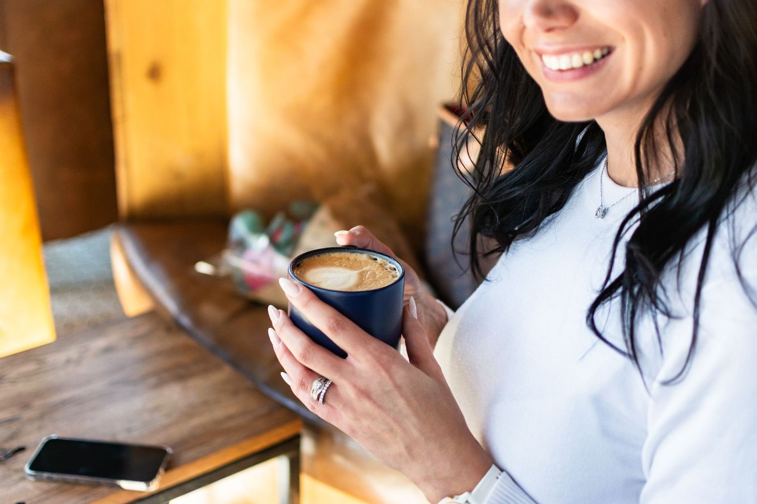 Person enjoying coffee while relaxing at wooden table.