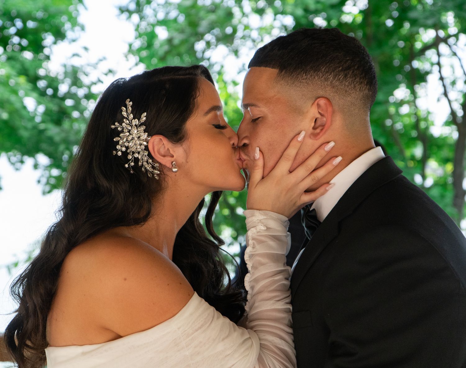 Romantic wedding couple sharing intimate moments in a lush green outdoor setting.