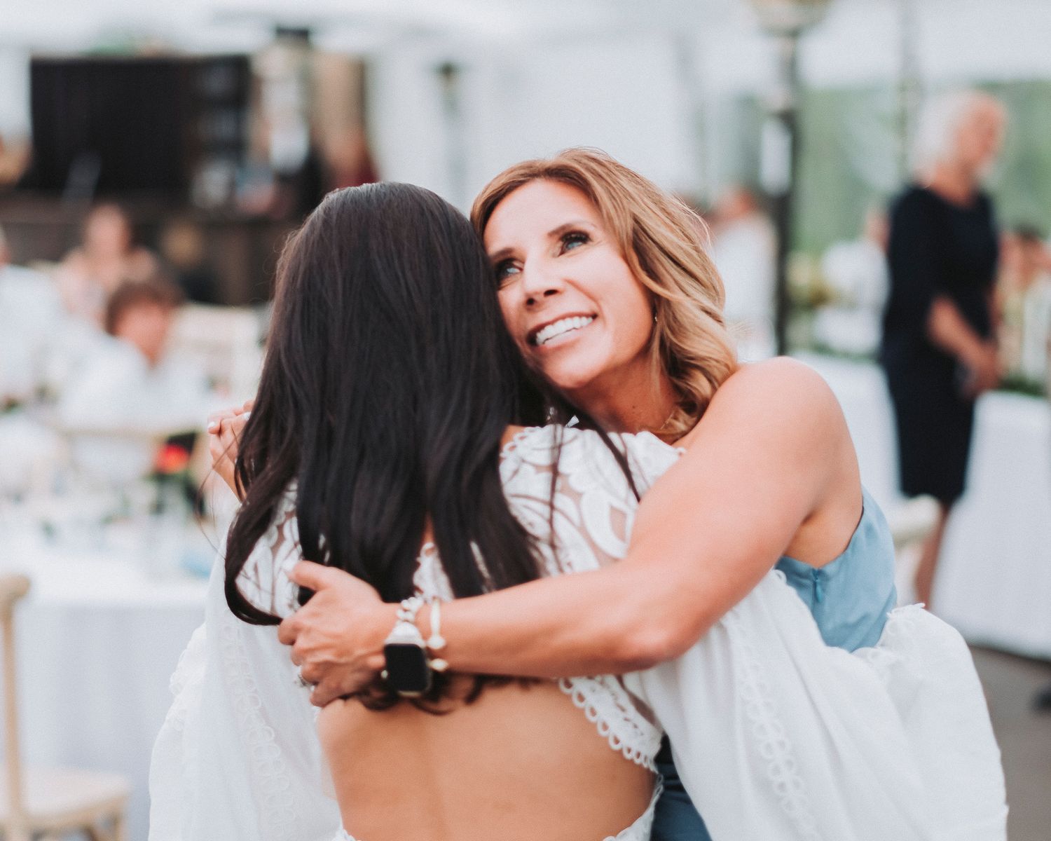 Mom hugging her daughter on her wedding day, beaming with pride and joy