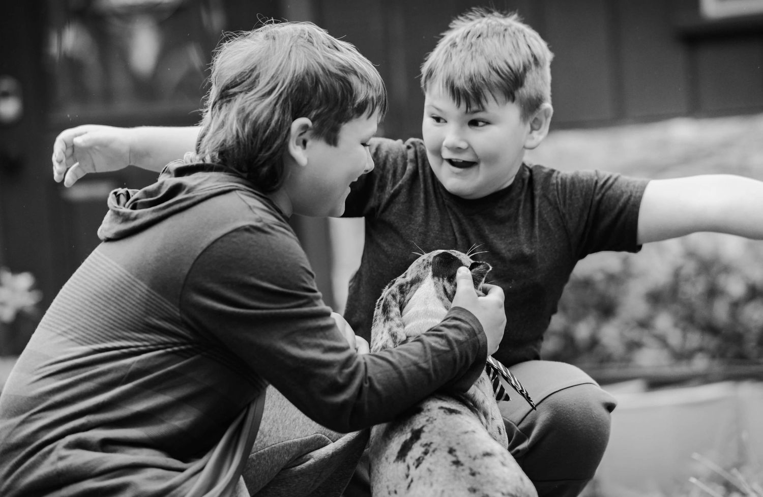 Two people share a joyful moment while playing with a small animal outdoors.