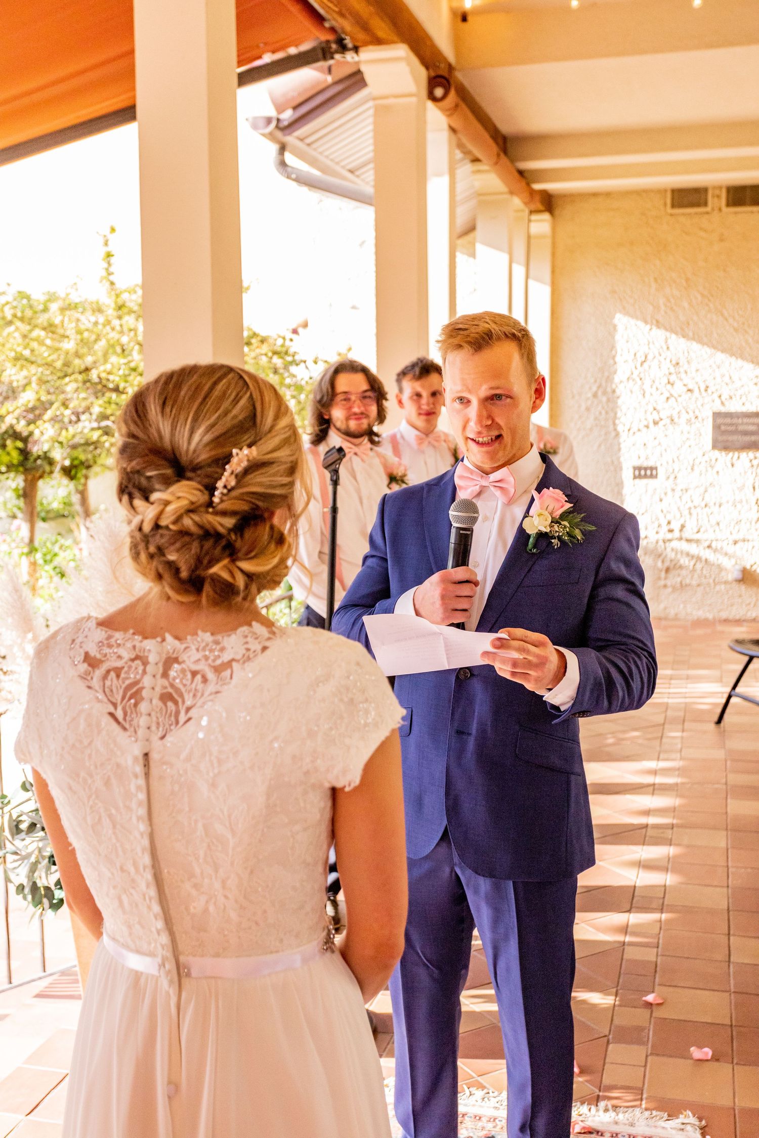 Couple exchanging wedding vows on a covered terrace with string lights overhead.