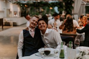 Two guests enjoying the wedding reception at an intimate dining table with wine glasses.