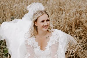 A white lace wedding dress flowing in a golden wheat field.