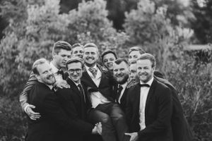 Group of groomsmen in tuxedos posing together for black and white portrait.
