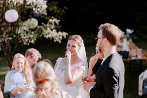 Wedding celebration outdoors with pink lantern and flowering trees in background.