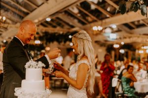 Newlyweds cutting their elegant white wedding cake together at the reception.