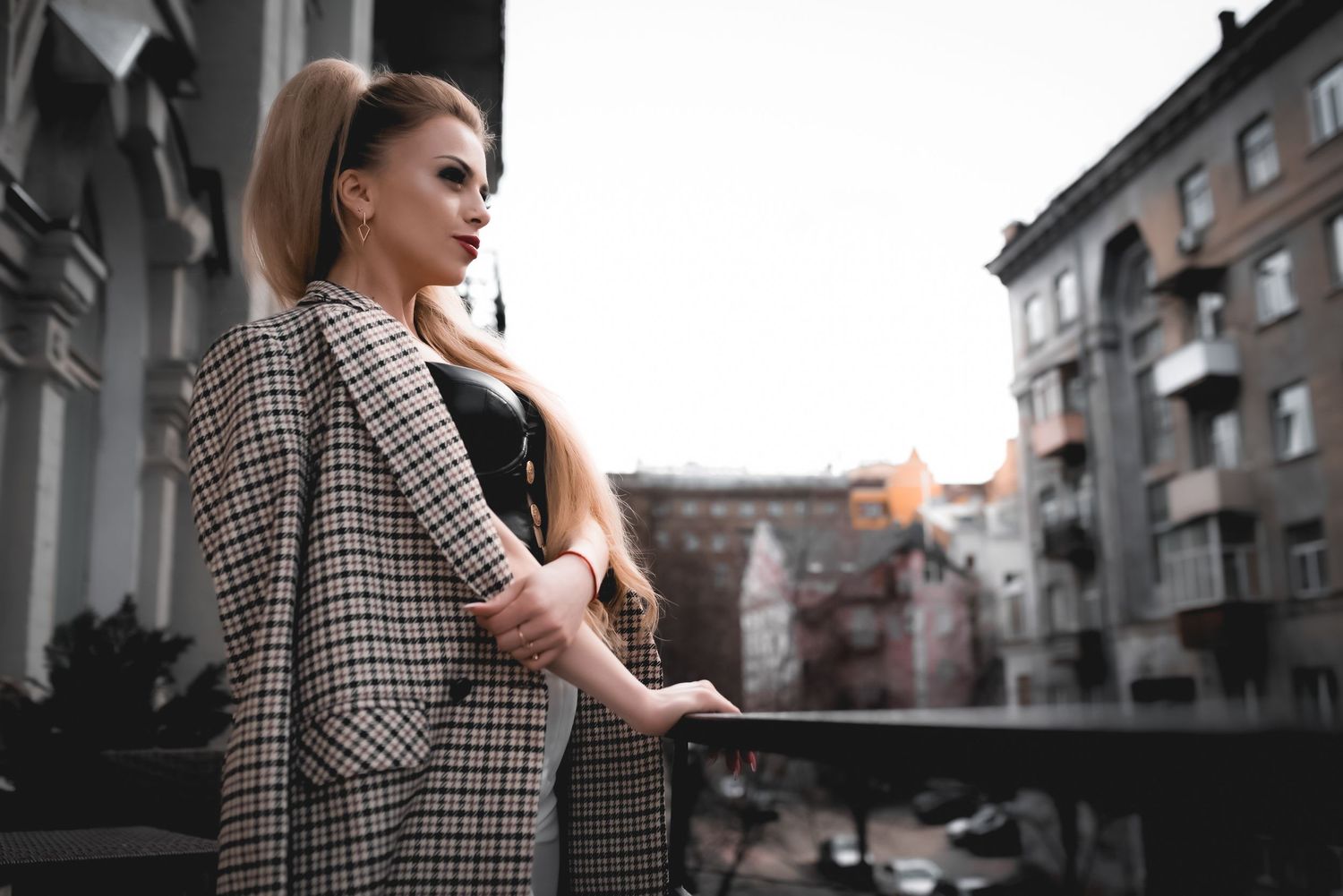 Urban fashion photography featuring checkered coat against architectural background in black and white.