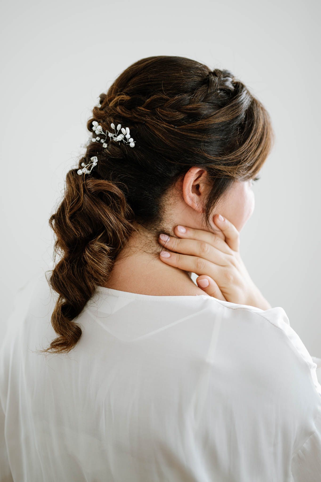 Elegant updo hairstyle with small white floral accessories shown from behind.