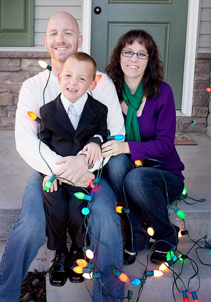 Holiday family portrait with colorful Christmas lights on the front porch.