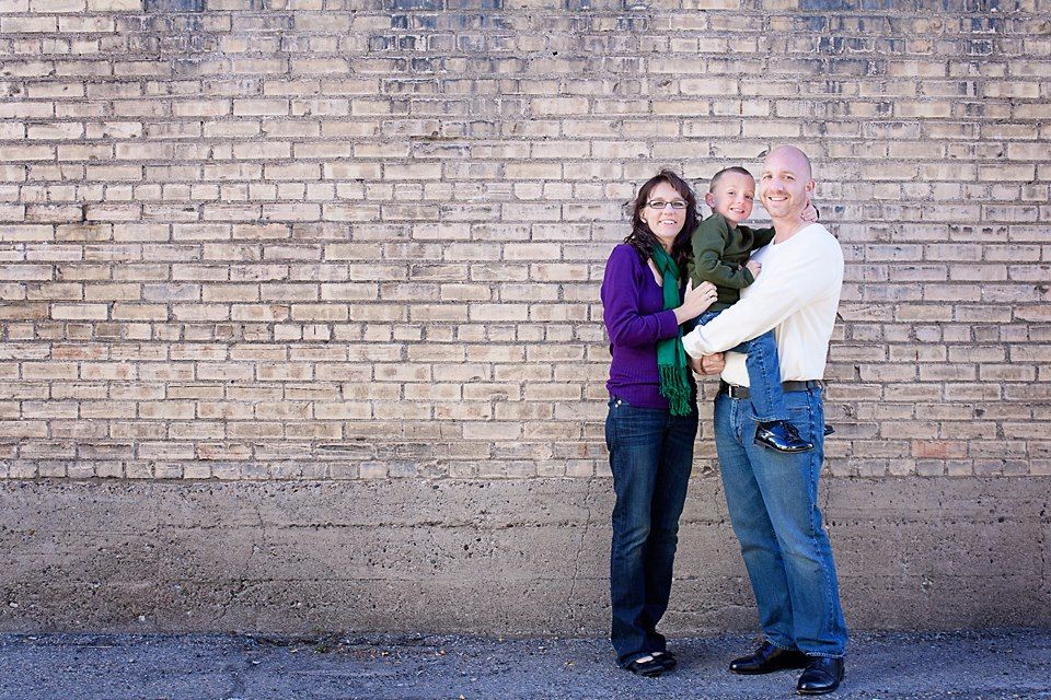 Couple embracing against weathered brick wall background.