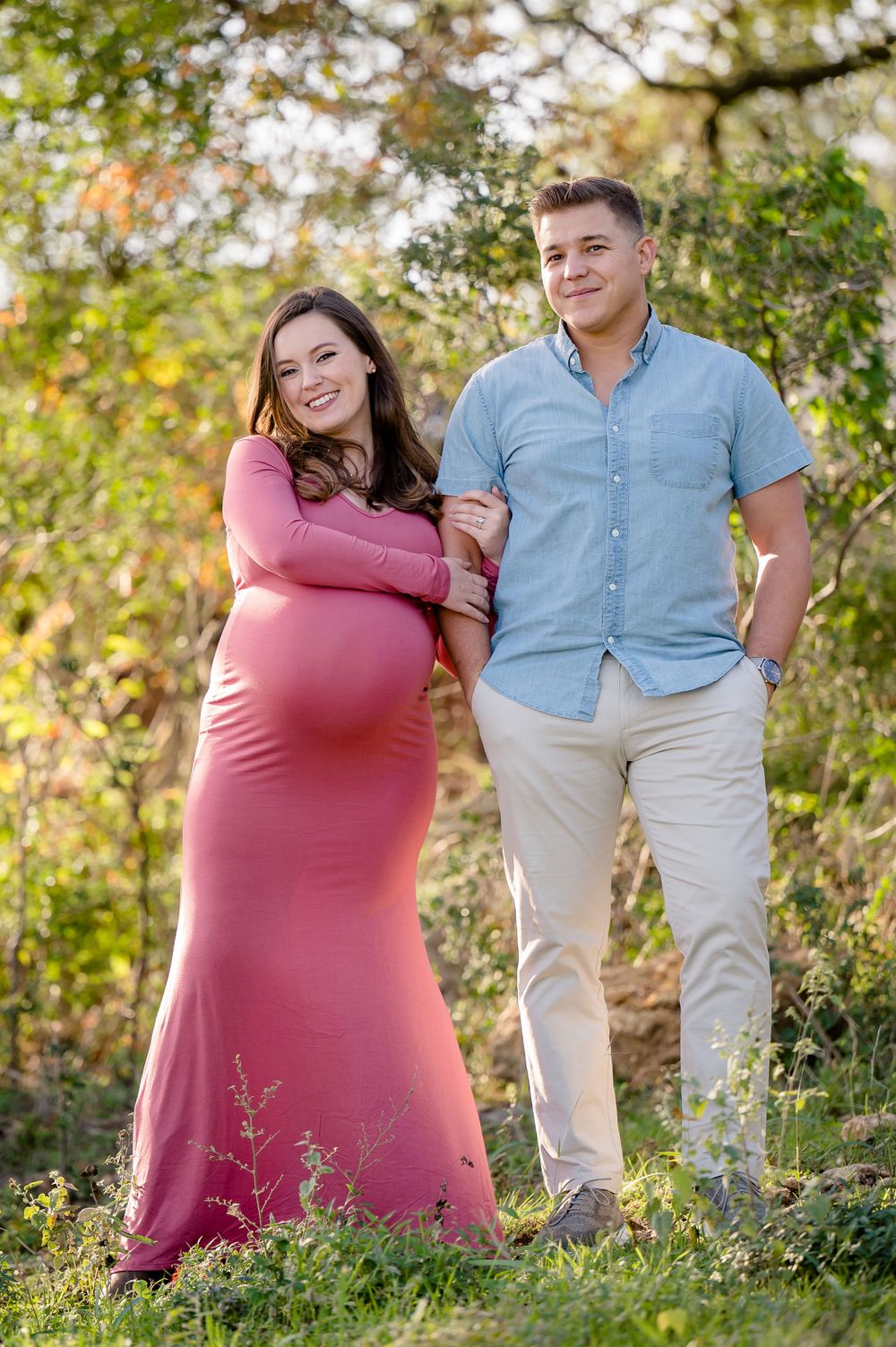 A couple poses together on a nature trail during their autumn maternity photoshoot.