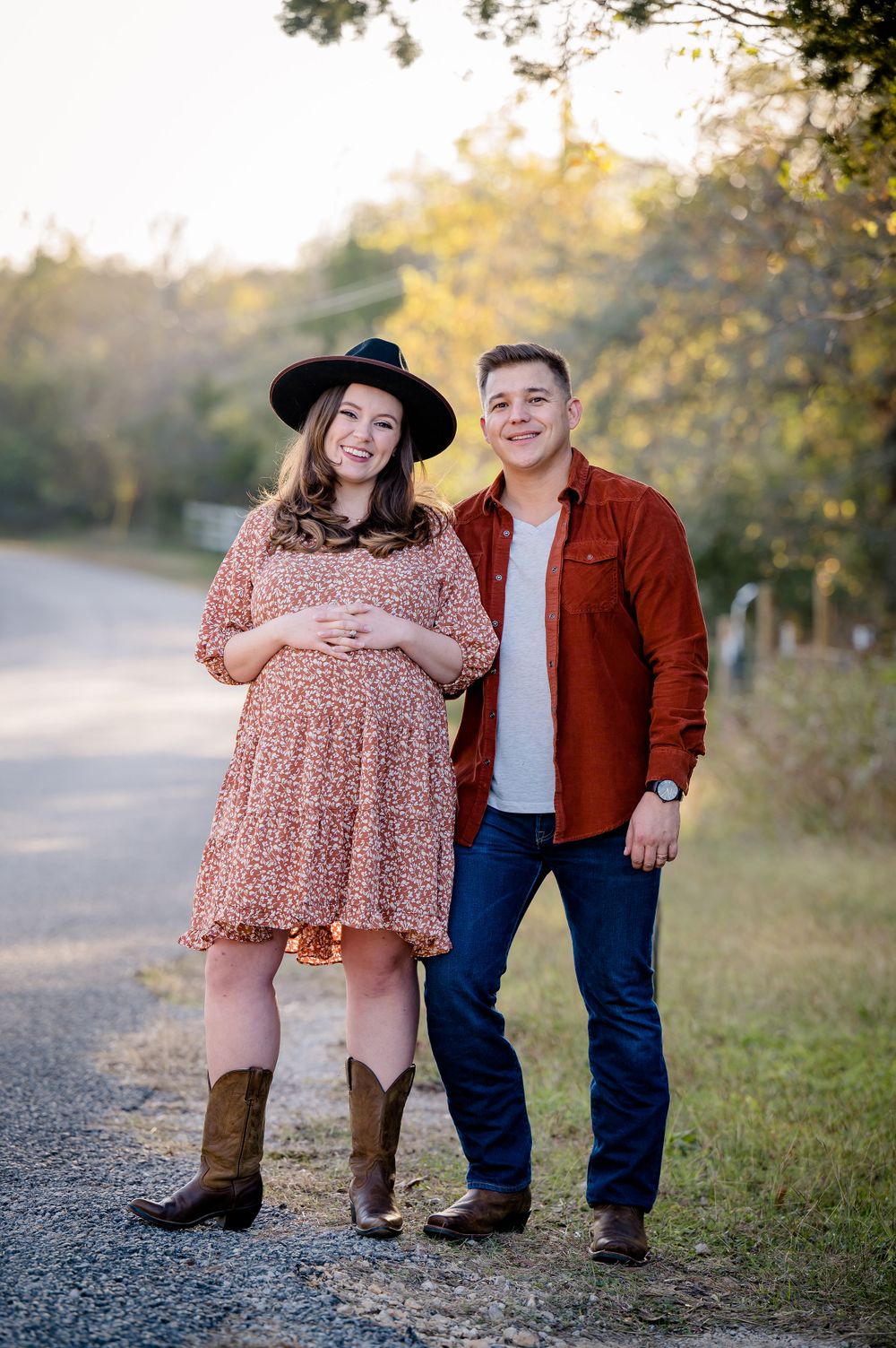 A couple poses on a country road during their fall maternity photoshoot.