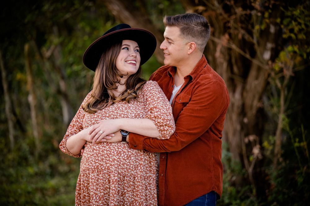 Intimate maternity portrait of couple embracing in autumn forest setting.