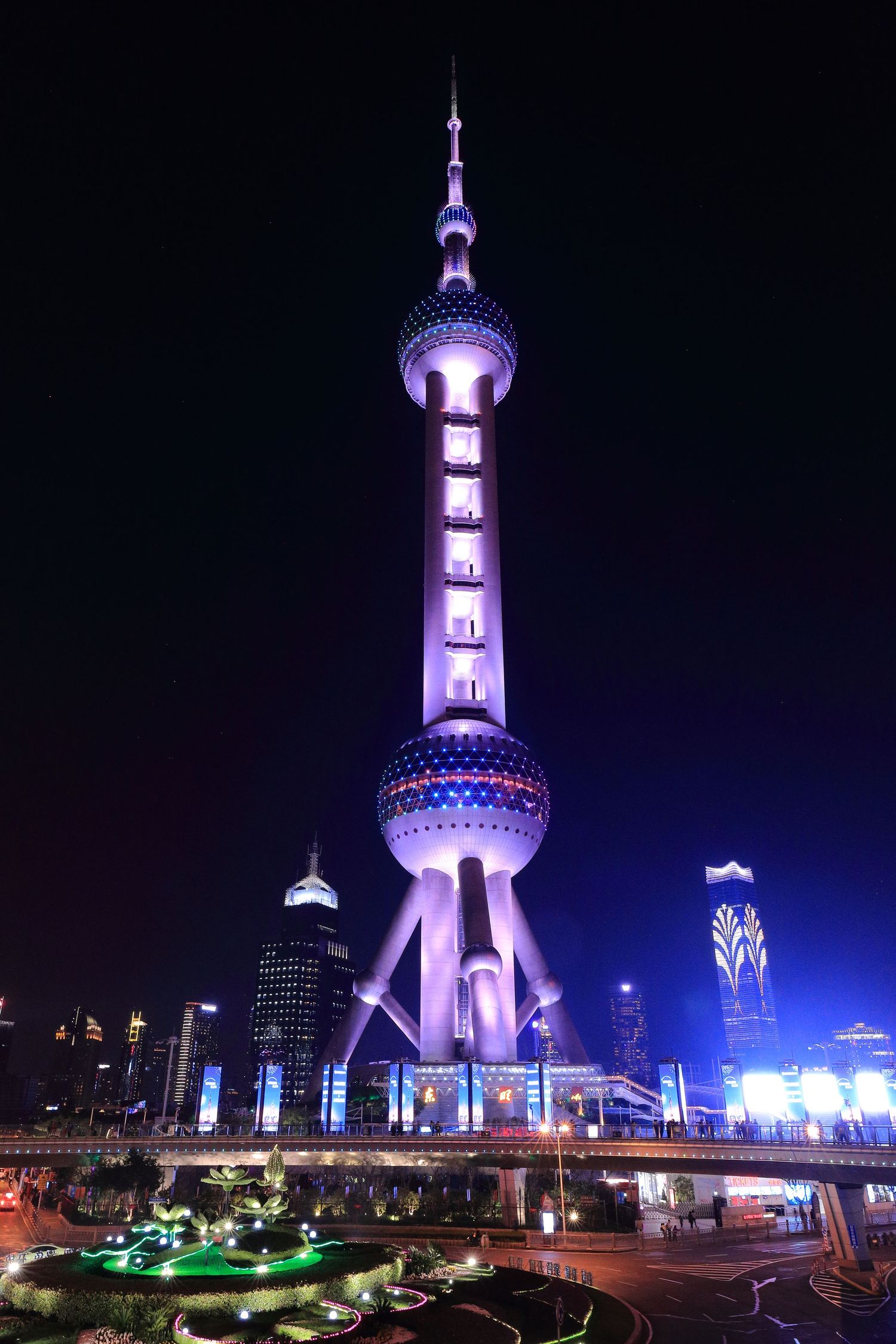 Illuminated Oriental Pearl Tower glowing purple at night in Shanghai's Pudong district.