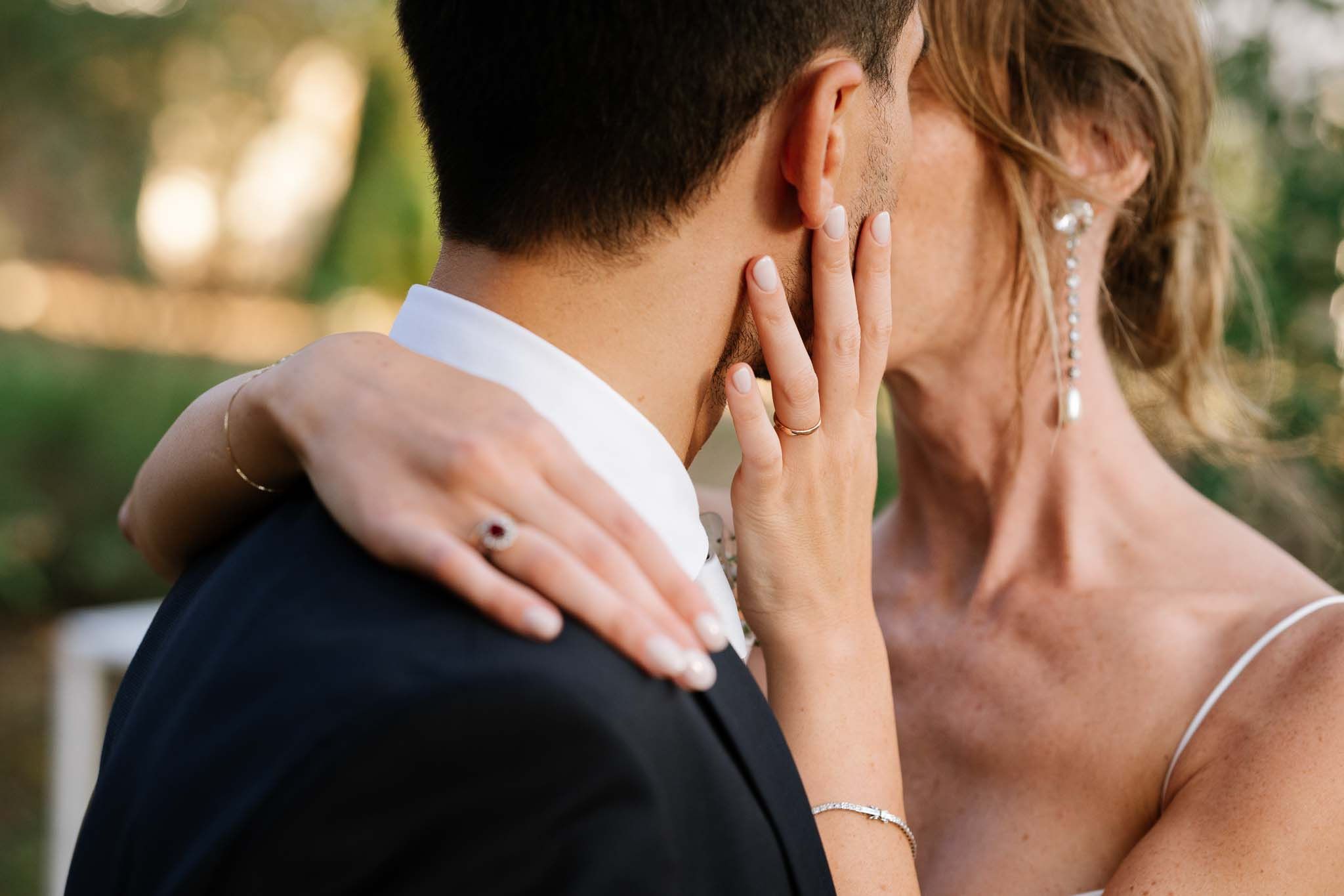 Close-up of tender embrace showing wedding ring and delicate jewelry details.