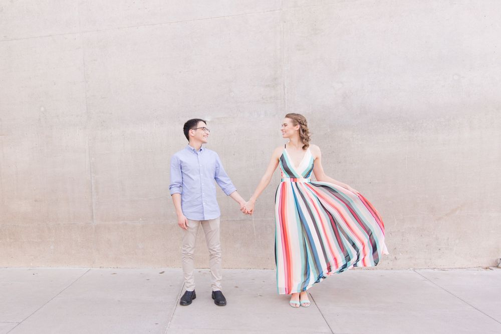 A carefree dance pose against a neutral wall wearing coordinated blue and striped outfits.