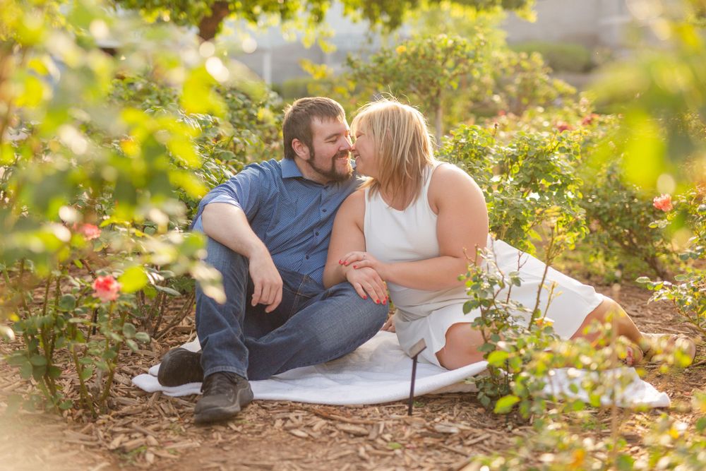 A couple sitting together in a garden surrounded by golden sunlight and flowers.