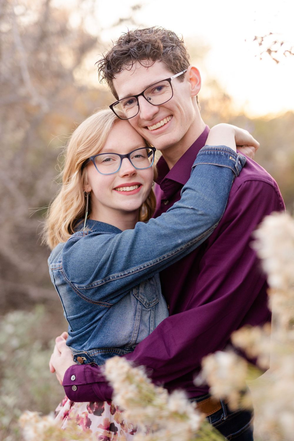 A couple shares a joyful embrace outdoors during golden hour photography.