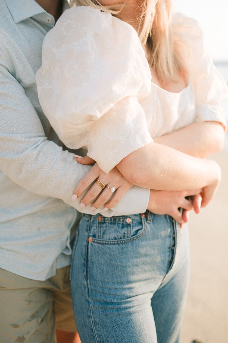 Close-up detail of couple embracing in white and denim casual beach attire.