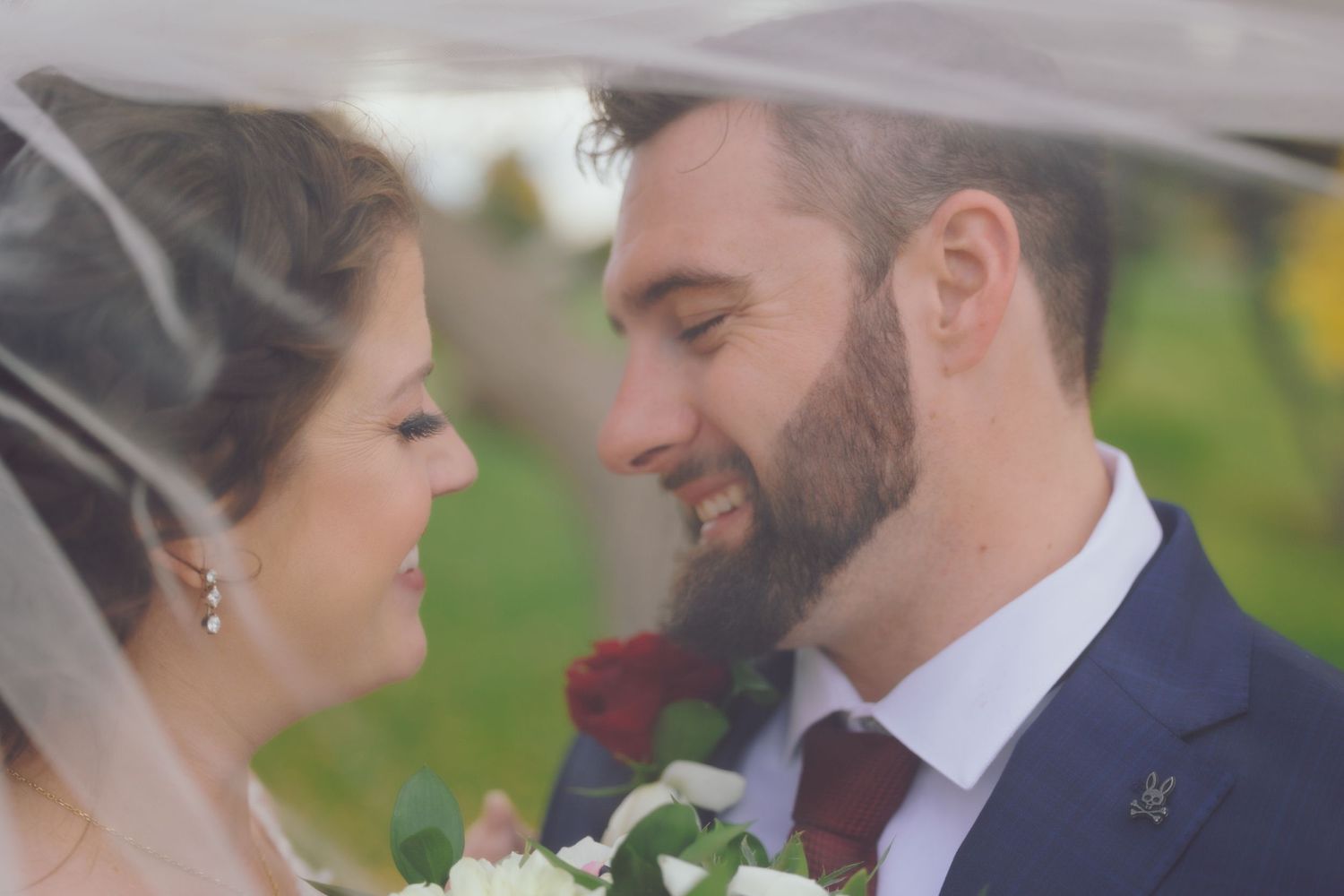 Bride and groom posing under veil