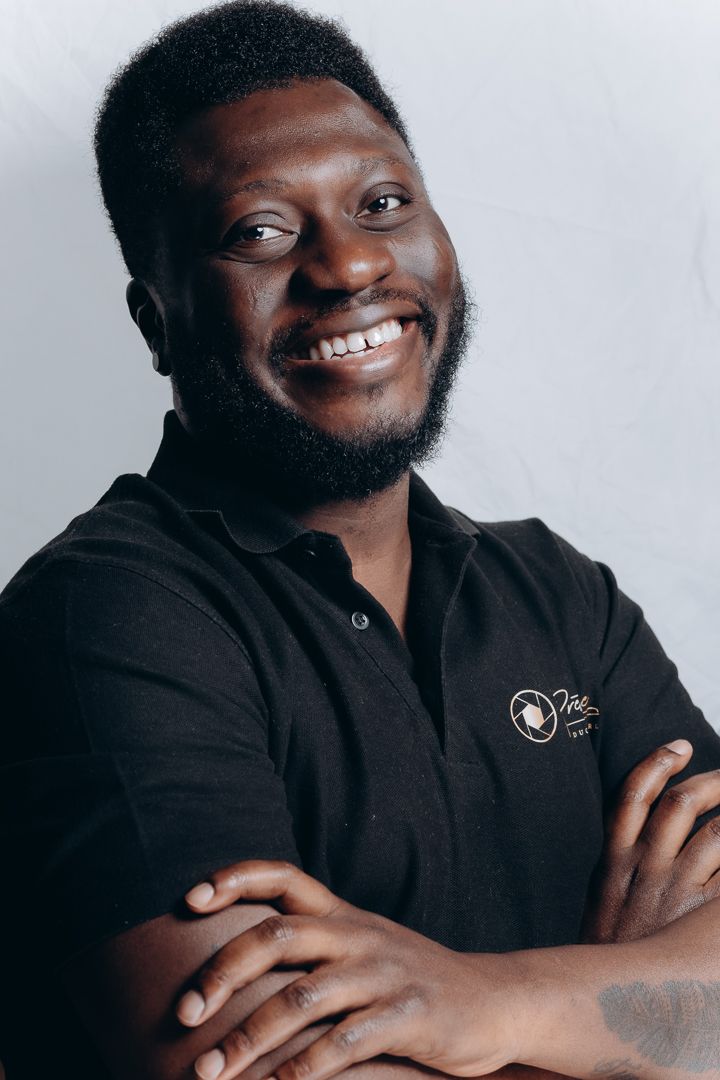 Professional headshot of person in black polo shirt smiling warmly at camera.