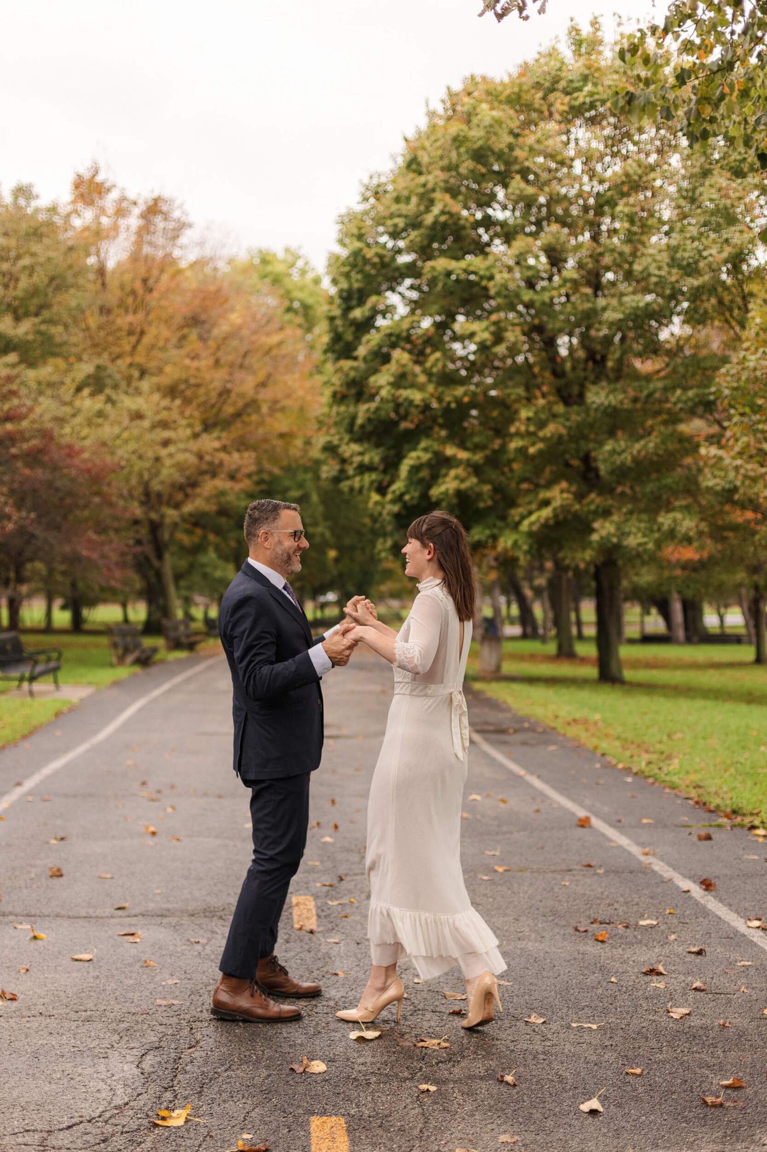 Couple sharing romantic moment on tree-lined path during autumn engagement session.